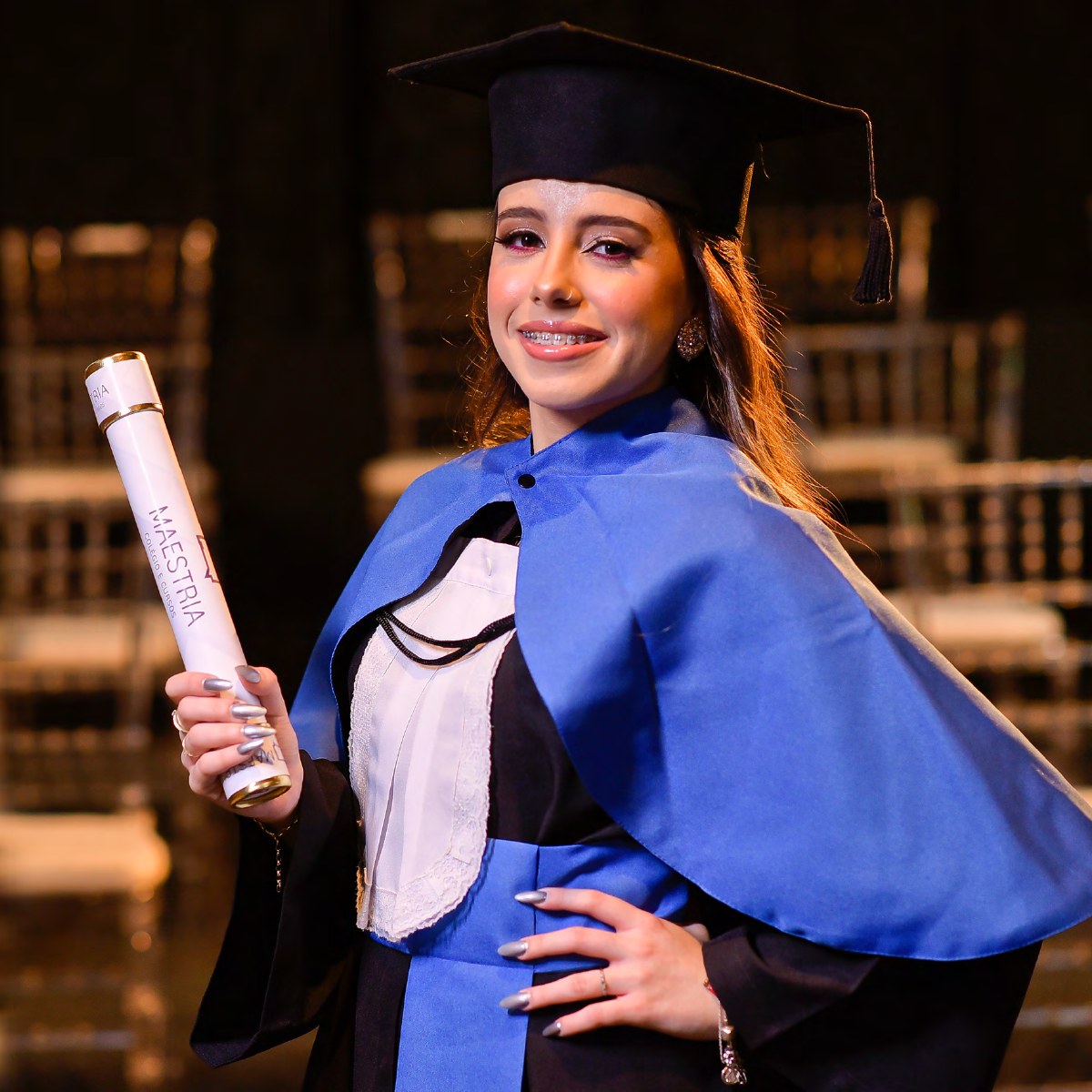 Formanda do Colégio Maestria com beca azul e diploma